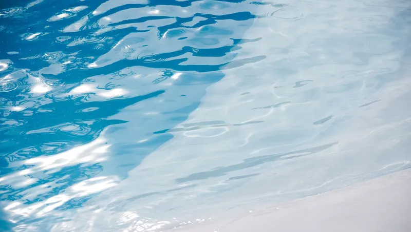 Suaves ondas en el agua de una piscina iluminadas directamente por el sol