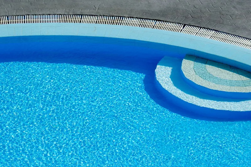 Escalones curvos de una piscina con agua azul cristalina tras el mantenimiento