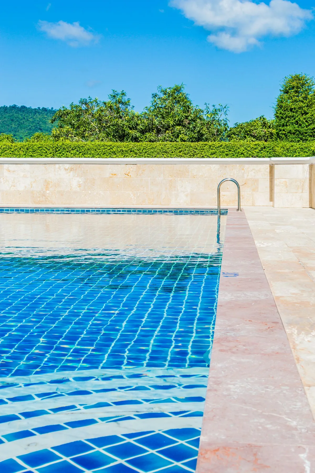 Piscina de agua turquesa con revestimiento de gres rodeada de vegetación mediterránea