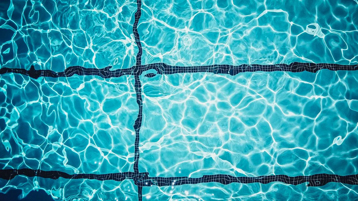 Vista cenital del agua turquesa y brillante de una piscina con líneas de gres
