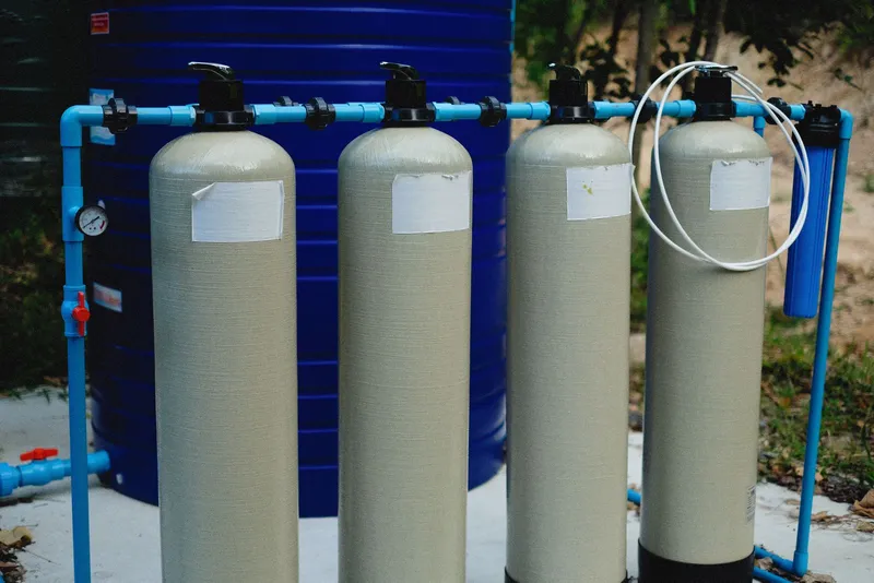 Equipo de tratamiento de agua con depósitos y tuberías azules, similar a la instalación de un clorador salino