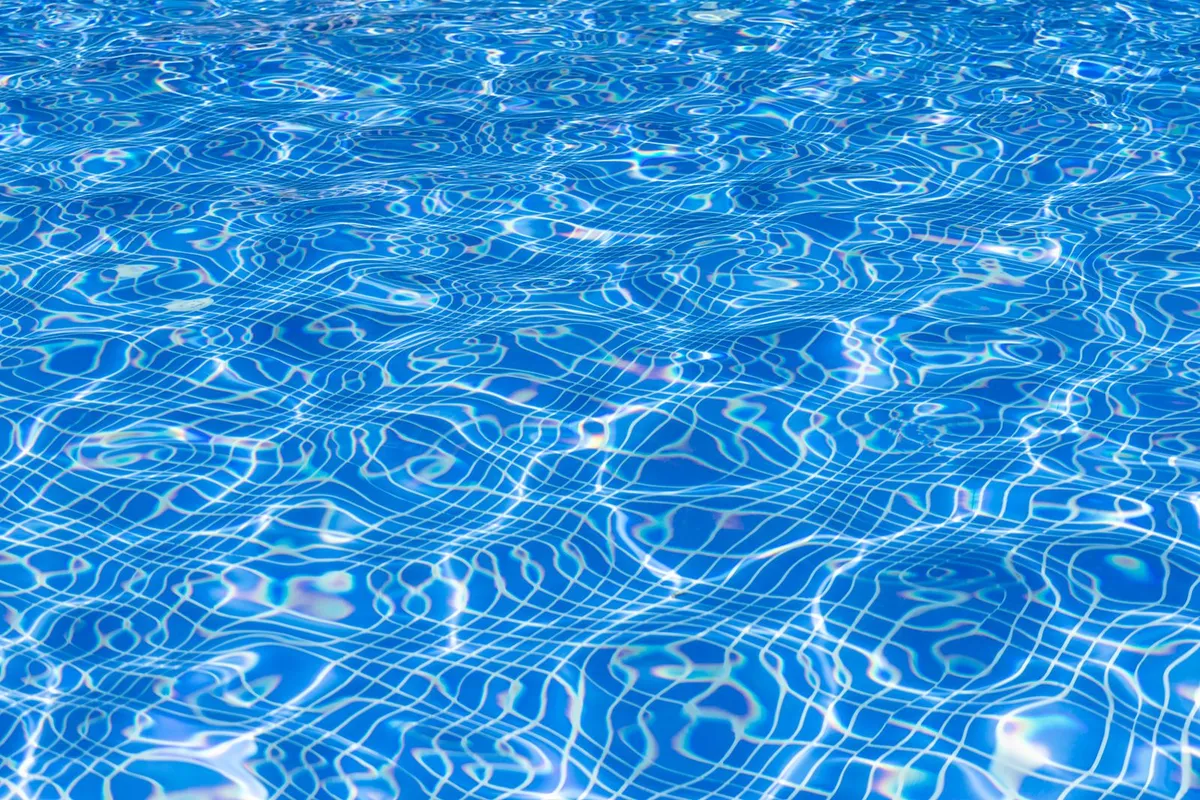 Superficie azul y luminosa de una piscina con reflejos del sol en el agua