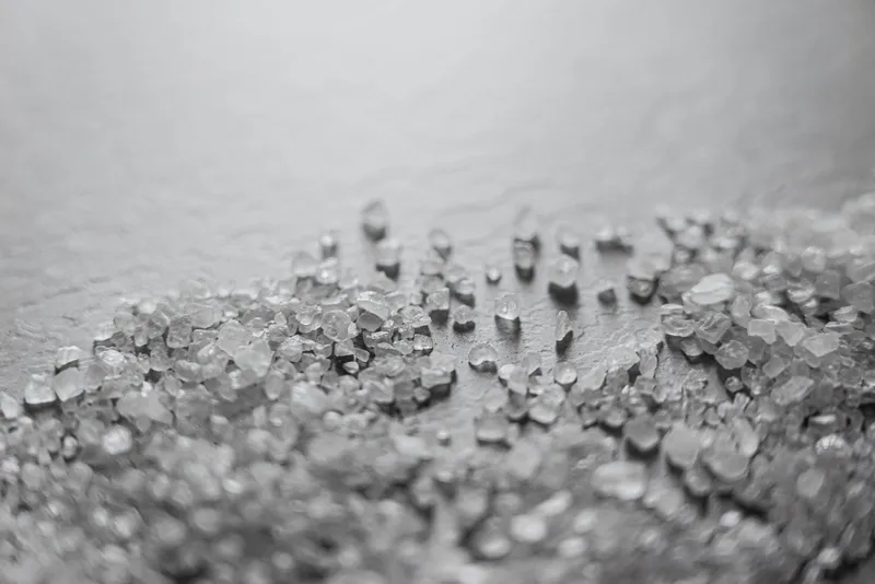 Cristales de sal gruesa blanca esparcidos sobre una superficie clara